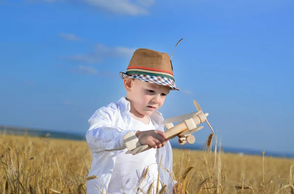 Мальчик летит на игрушечном самолете на пшеничном поле — стоковое фото