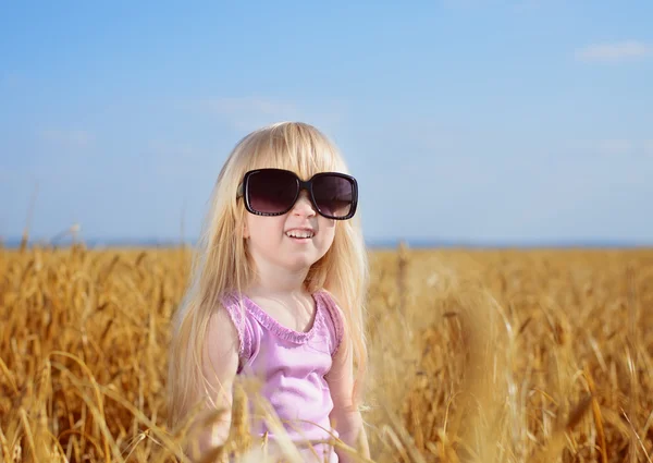Söt liten blond flicka spelar i ett vete fält — Stockfoto