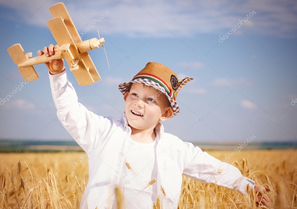 Trendy young boy playing in a field with a plane
