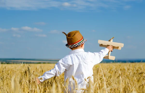 Aranyos kisfiú repül egy játék gép, egy wheatfield — Stock Fotó