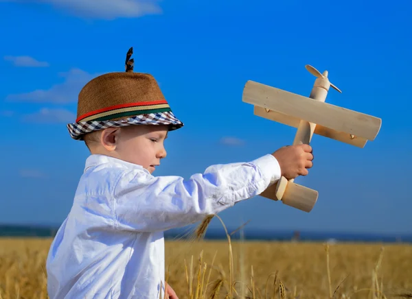 Aranyos fiatal fiú játszik egy fából készült kétfedelű repülőgép — Stock Fotó