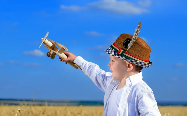 Серьезный маленький мальчик играет с игрушечным самолетом — стоковое фото