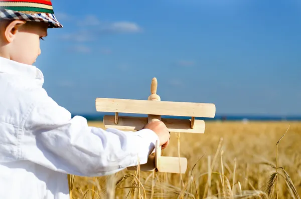 Little boy playing in farmland with a toy airplane — Stock Photo, Image