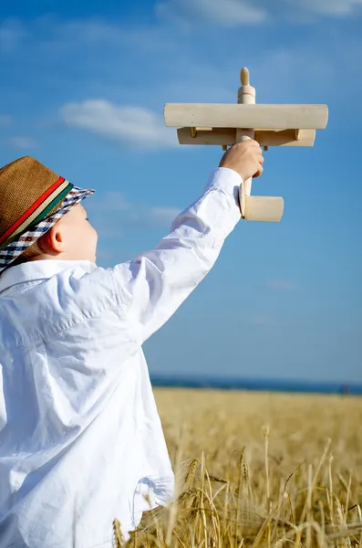 Bir uçak ile oynarken sevimli şapka içinde küçük çocuk — Stok fotoğraf
