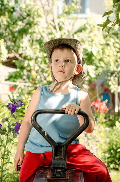 Nachdenklicher kleiner Junge sitzt in einem Bauerngarten — Stockfoto