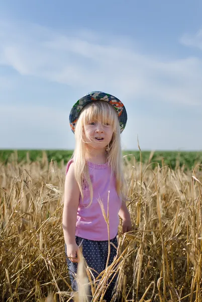 Kleines Mädchen geht in einem Weizenfeld — Stockfoto