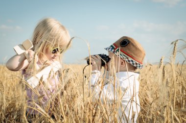 Two little children playing in a wheat field clipart