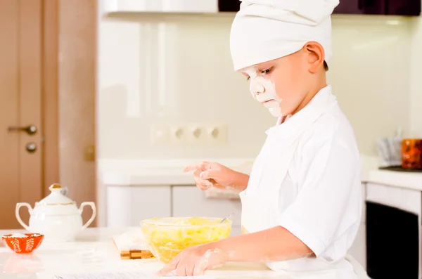 Kleiner seriöser Koch konsultiert sein Rezeptbuch — Stockfoto