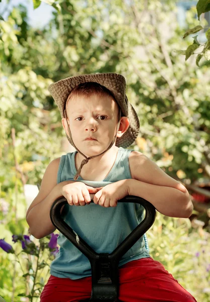 Задумчивый мальчик сидит в сельском саду — стоковое фото