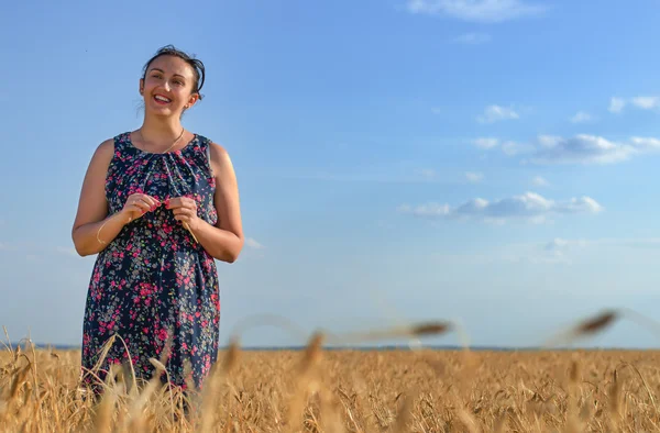 Altın alanındaki buğday, gülümseyerek mutlu bir kadın — Stok fotoğraf