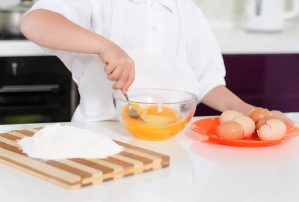 Giovane ragazzo cottura uova montate — Foto Stock