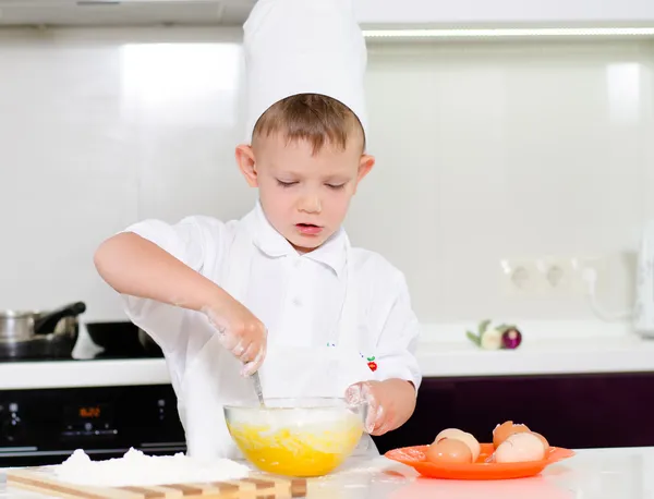 Giovane ragazzo cottura uova montate — Foto Stock