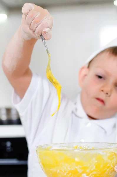 Schattige jonge jongen leren Baal een cake — Stockfoto