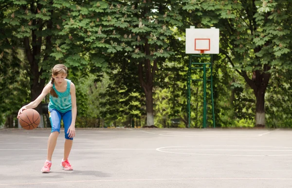 Menina jovem driblando uma bola de basquete — Fotografia de Stock