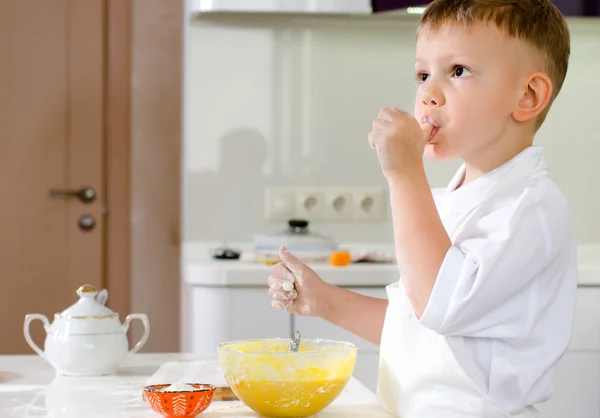 Cut little chef tasting his batter mixture — Stock Photo, Image