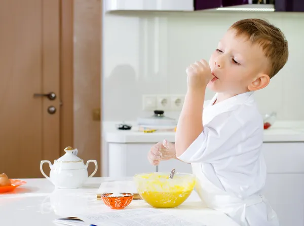 Cut little chef tasting his batter mixture — Stock Photo, Image