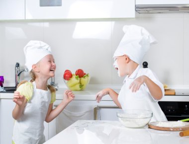 Happy little boy and girl baking in the kitchen clipart