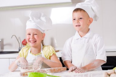 Happy little boy and girl cooking in the kitchen clipart