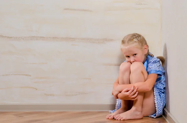 Sad young girl sitting in corner — Stock Photo, Image