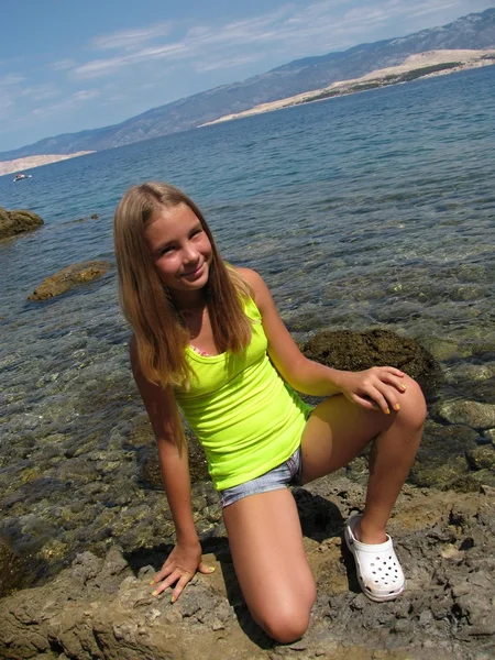 Mladá dívka na skále u moře — Stock fotografie