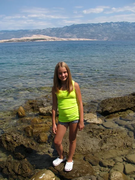 Junges Mädchen auf einem Felsen am Meer — Stockfoto