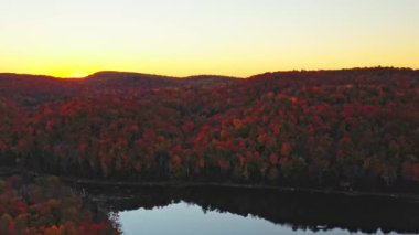 Parktaki renkli ağaçların arkasında gün batımında Mont-Loup-Garou 'dan insansız hava aracı mermisi yavaşça düşüyor.