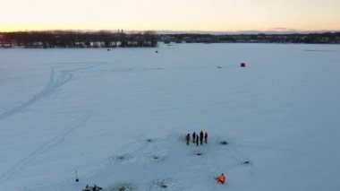 Bir grup buz balıkçısı tarafından desteklenen hava aracı kışın gün batımında diğer balıkçıları ortaya çıkarıyor.