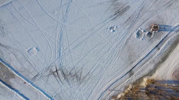 凍った氷をまっすぐに撮影し 氷の釣りの穴 誰かが歩くと冬に釣りの人々のグループを明らかに空中ドローンビュー — ストック動画