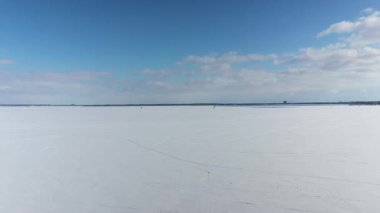 Oka 'daki buzun üzerinde mavi gökyüzü ve uçurtma sörfçüsüyle donmuş iki dağ gölünün insansız hava aracı görüntüsü.