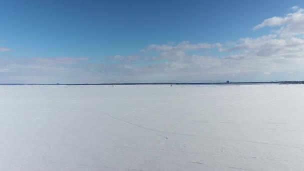 青い空と丘の氷の上にカイトサーファーと凍結湖の2つの山の空中ドローンビュー — ストック動画