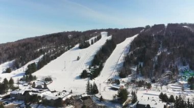 Laurentians 'taki St-Sauveur' de güzel güneşli bir kış gününde dağlardan inen kayakçıların hava aracı görüntüsü devam ediyor.