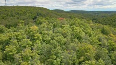 Ağaçların üzerinden uçarak Montagnes Noires parkının panoramasını gösteriyor. Parkın ortasındaki gözetleme kulesine doğru ilerliyor.