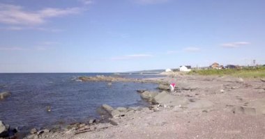 Lady by the shore picking up stones