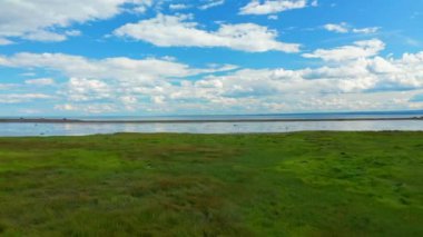 Düşük irtifada İHA uçuşu, Gaspesie 'deki Ilets les Mechins' de, St. Lawrence nehrinin kıyısında, arka planda beyaz bir kaya adası ve bir yelkenli teknesi görünüyor.