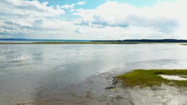Hava aracı videosu, sağdan sola dönüyor, alçak irtifada, suyun üstünde, kıyıdaki balıkçılların yanında, Carleton 'daki Parc de la Grande Envole' da.