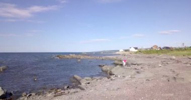 Lady by the shore picking up stones