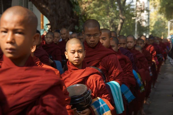 Буддийские новички ходят собирать милостыню и подношения в Амарапуре возле Мандалая — стоковое фото