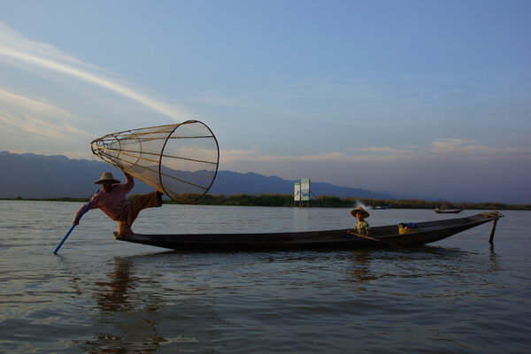 Fishermen on Inle Lake in Myanmar (burma) using unique technique of leg-rowing and conical fishnet.