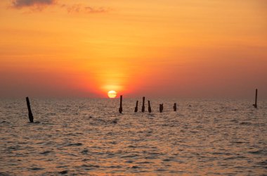 Denizde güzel bir omega gün batımı ve Tayland 'ın Pilai sahilinde güzel bir turuncu gökyüzü. Denizde eski ahşap köprü.