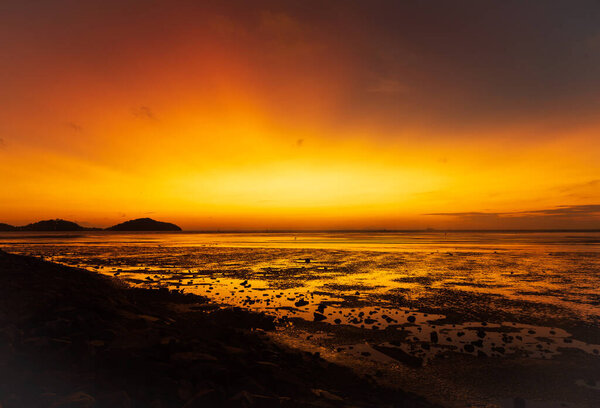 Scene of beautiful orange sky in the morning at Saphanhin public beach, Phuket, Thailand.