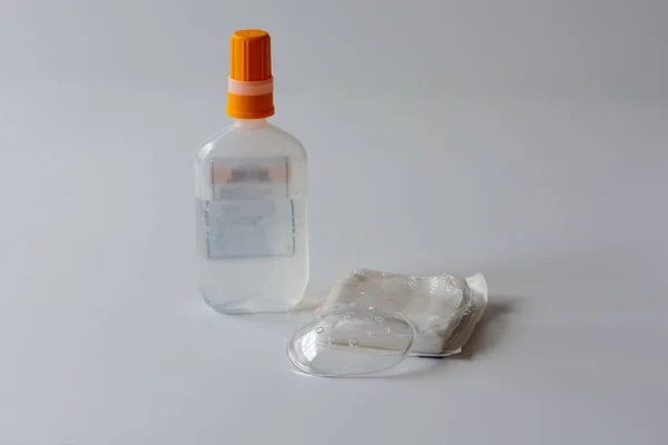 A clear plastic protective eye shield , a package of gauze and normal saline for eye cleaning after cataract surgery.