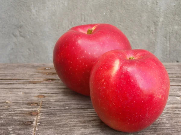 Dua apel merah di atas meja kayu — Stok Foto