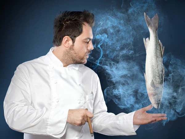 Jovem chef bonito com peixe robalo defumado — Fotografia de Stock