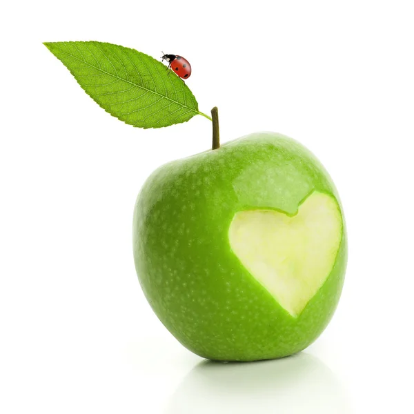Green apple with cut heart and ladybird — Stock Photo, Image