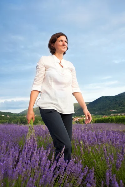 Kvinnan promenader genom lavendel fält — Stockfoto