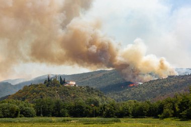 Slovenya 'daki Miren Kalesi yakınlarında şiddetli rüzgar ve kuraklık sırasında helikopterle orman yangınına karşı mücadele