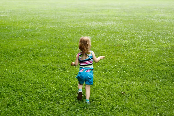 Criança pequena correndo por um prado — Fotografia de Stock