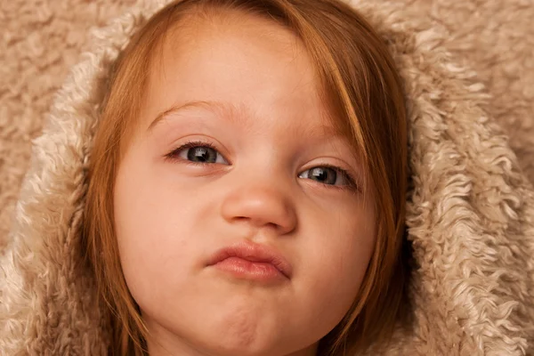 Jovem criança puckering lábios sob capa de pele — Fotografia de Stock