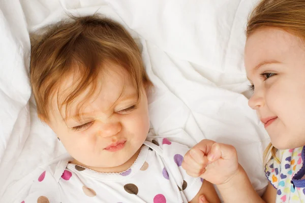 Silly baby in sheets with big sister — Stock Photo, Image
