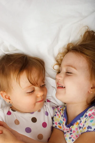 Systrar spela i sängen — Stockfoto